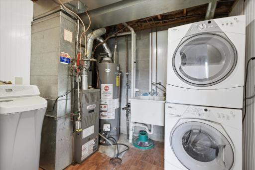 Utility room with front loading washer/dryer, water softener & newer water heater.
