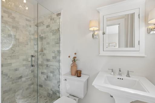 Beautifully appointed primary 3/4 bath with a tiled walk-in shower and elegant glass doors.