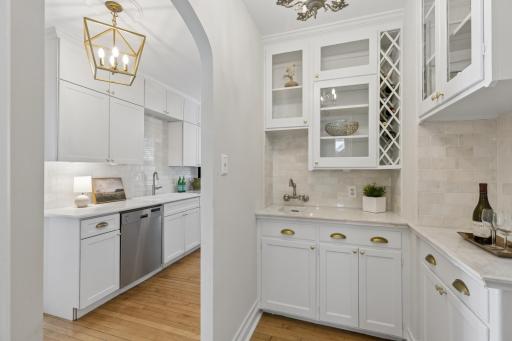 Tucked just off the kitchen, the wet bar offers glass-front cabinets and wine slots.