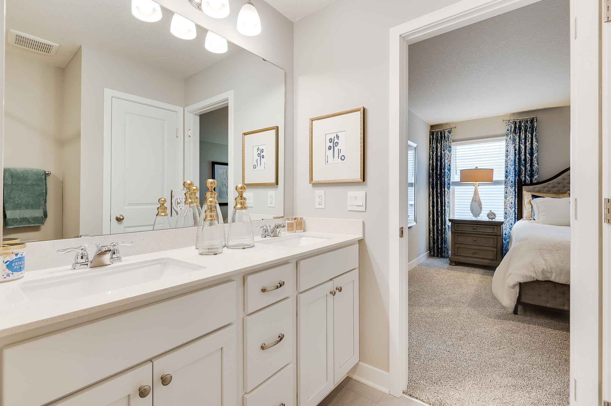 A peak inside the bathroom off the Primary Bathroom. Notice the extra high cabinets and double-bowl Quartz covered vanity with loads of storage! Photo is of model home. Colors and options may vary. Ask Sales Agent for details.