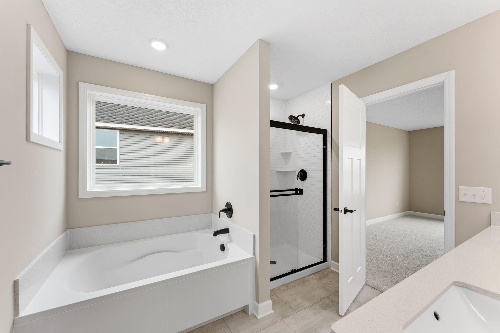 A glass-enclosed shower with Sterling Vikrell surround, built-in seating and an oversized shower head are featured in the bathroom