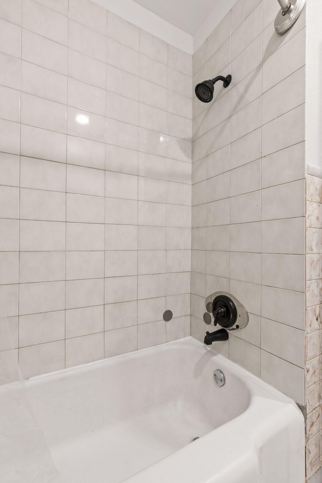 Tiled tub and shower surround in the main-level full bathroom.