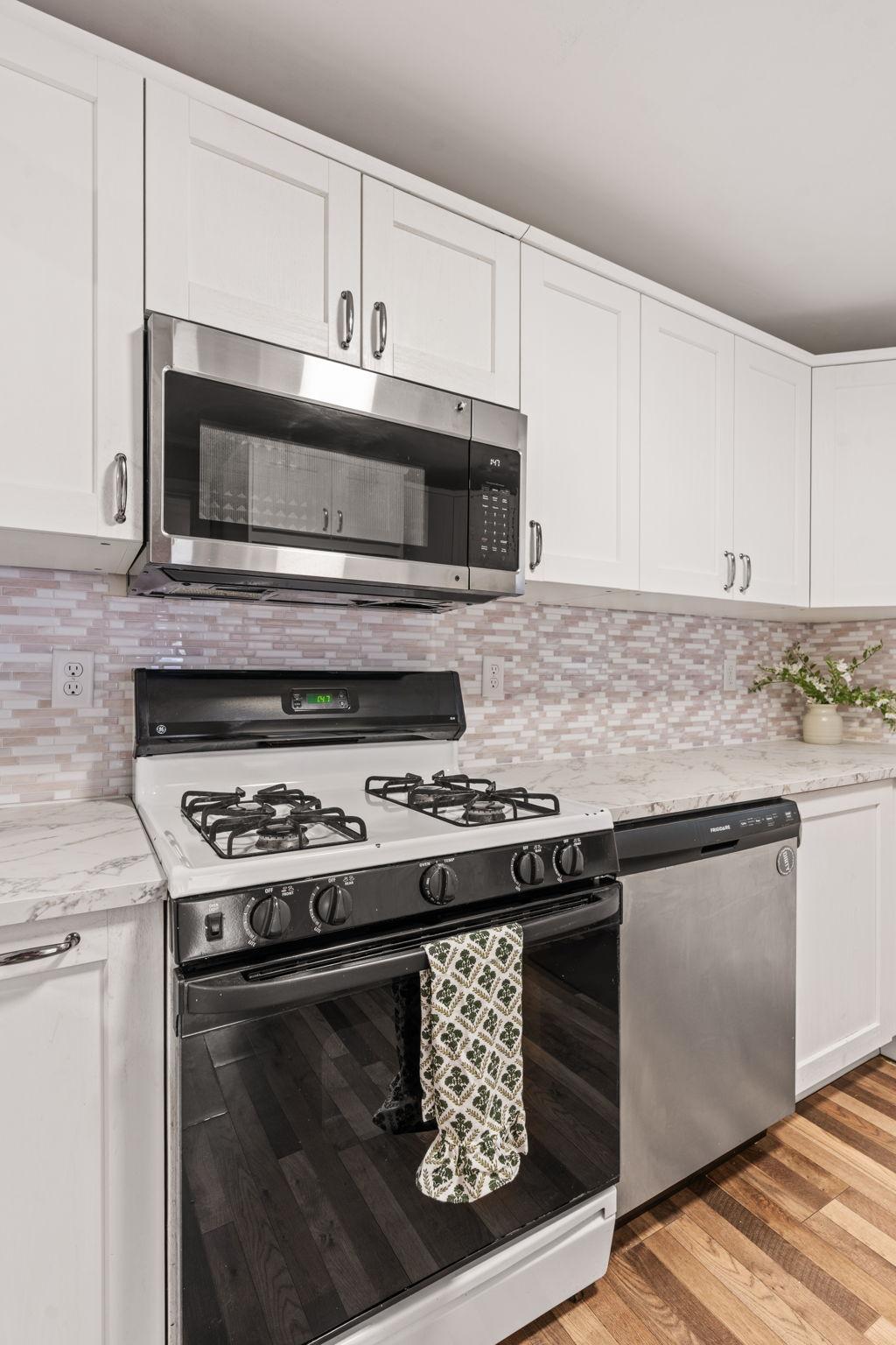 Stainless steel appliances and a neutral backsplash complete the kitchen.