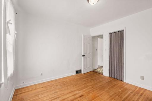 Bright bedroom with hardwood floors and neutral finishes.