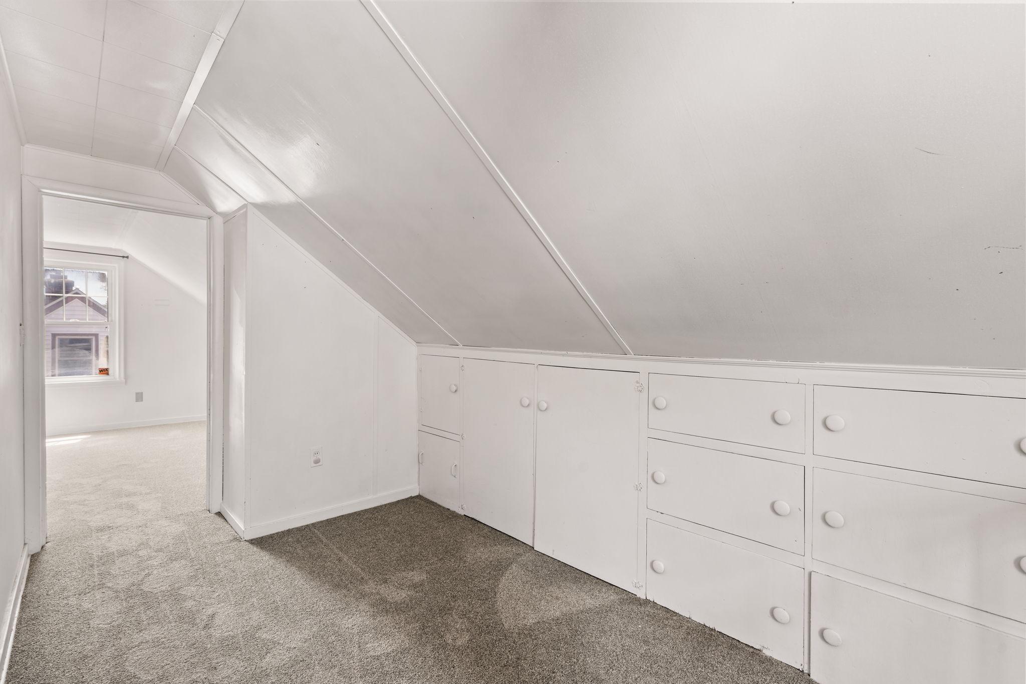 Upper-level space with built-in drawers and charming sloped ceilings.