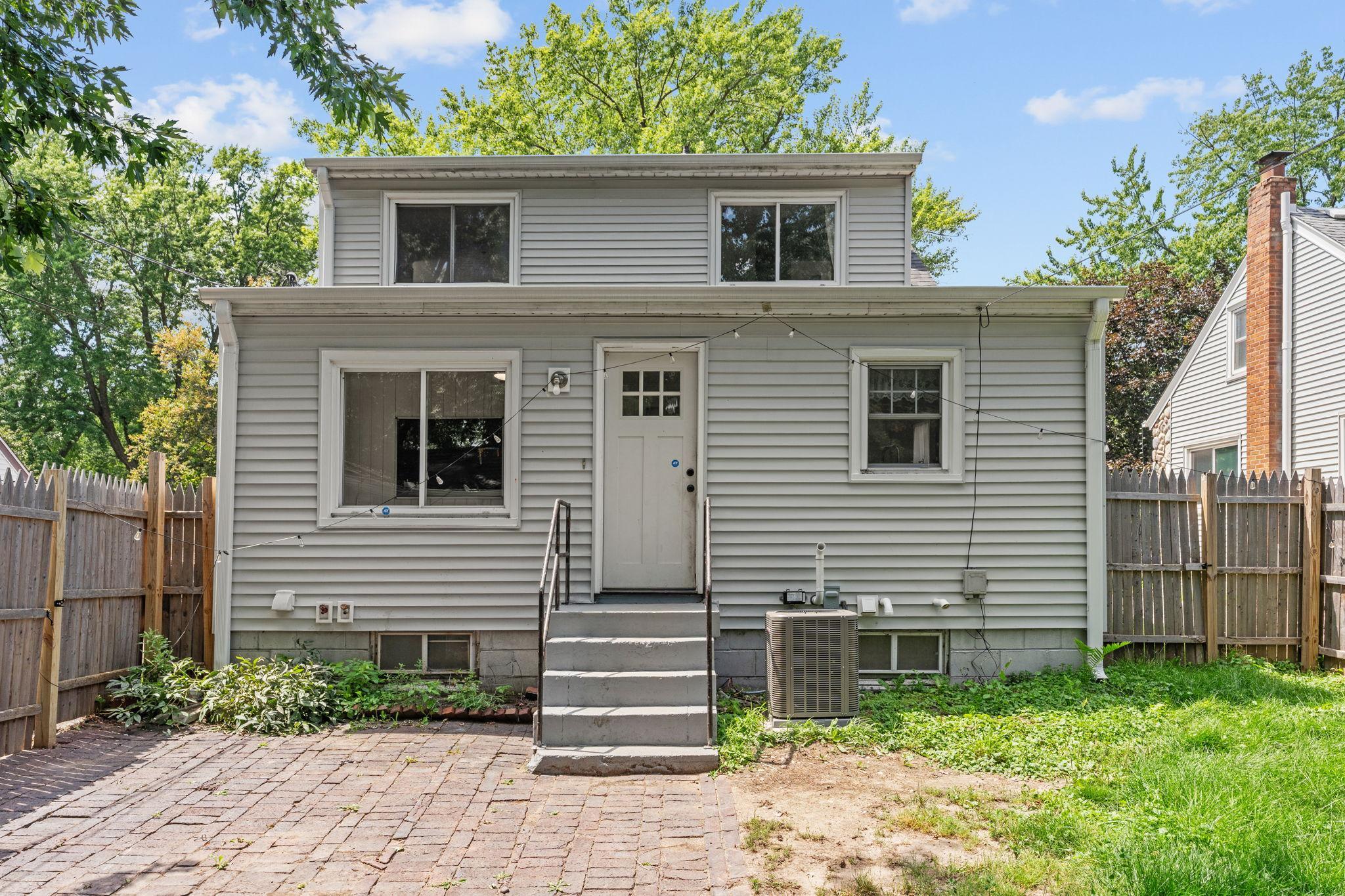 Rear exterior view showcasing the new siding and gutters, plus convenient backyard access.