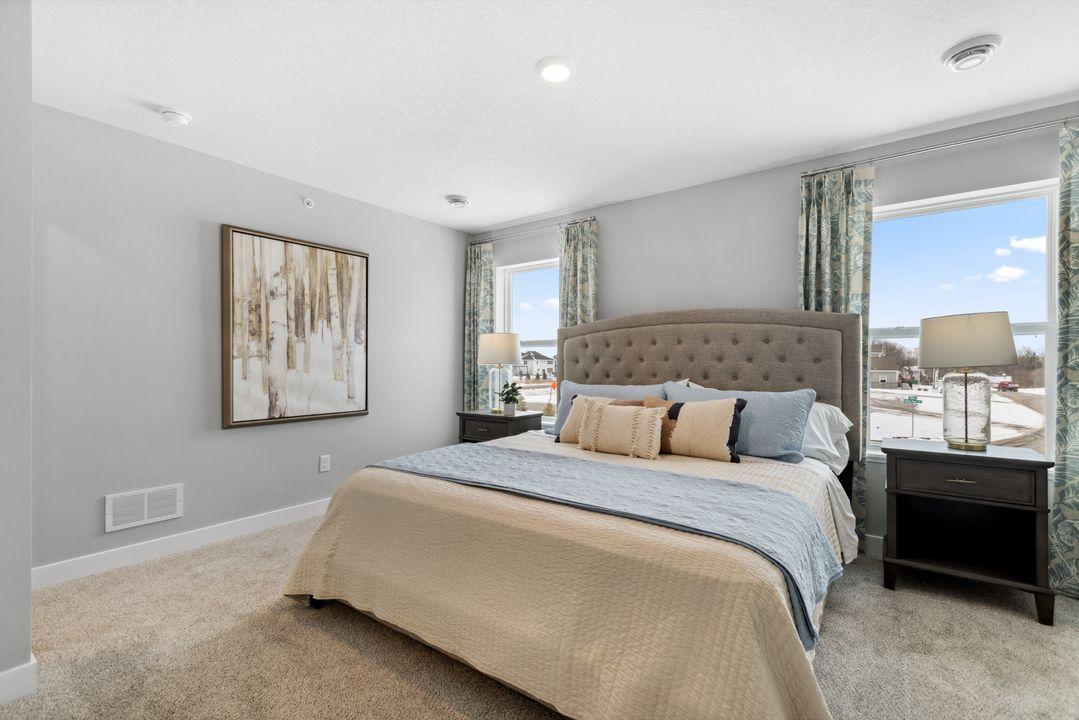 The generous primary suite offers comfort and privacy. There's immediate access to a private bathroom that features dual sinks and a large shower. Photo is of model home. Colors and options may vary. Ask Sales Agent for details.