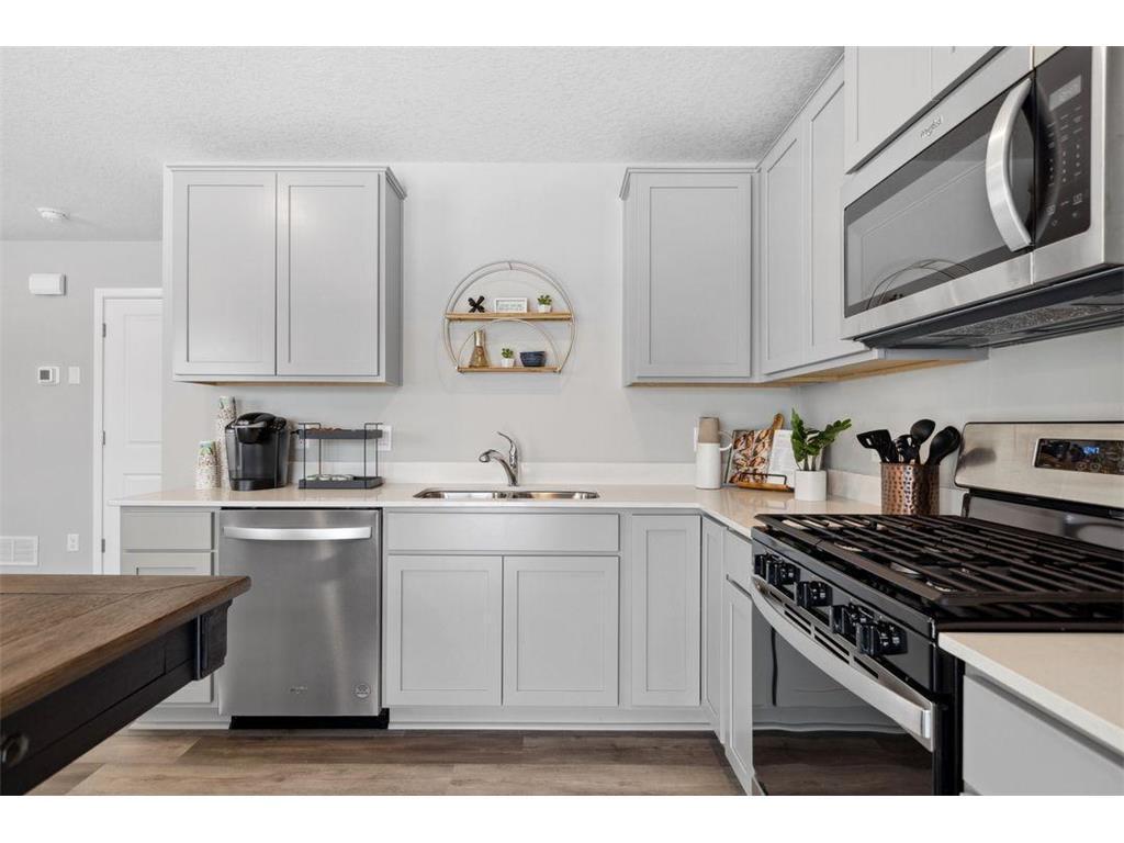 Kitchen with beautiful cabinetry, gas range, microwave and quartz countertops.