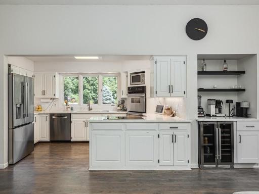The open kitchen stays bright with three windows overlooking the fountain and rock garden and with the white cabinetry and countertops. The hardwood flooring on the main floor were installed in 2019.