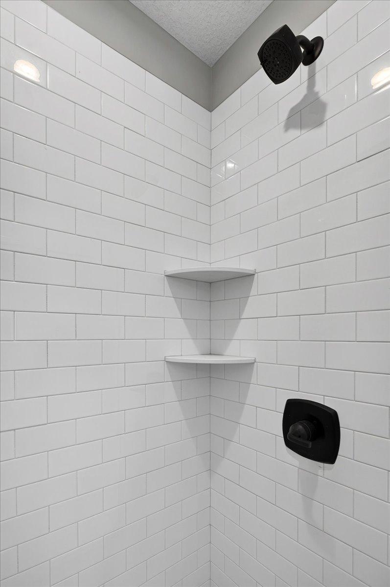 PHOTO OF A DIFFERENT HOME WITH SIMILAR PLAN AND FINISHES. Primary Deluxe Bath Shower features Tile Wall Surround.