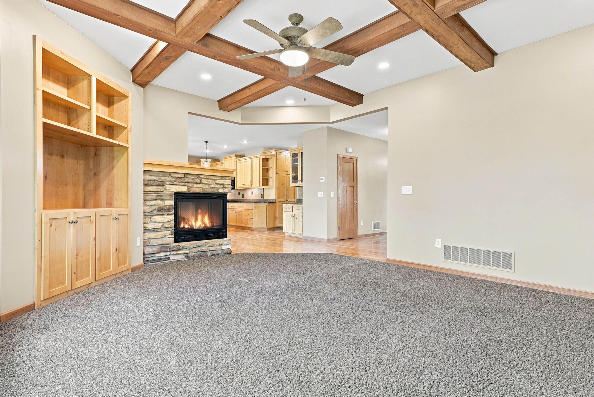 Just beyond the inviting front entry way, the living room is host to gorgeous stunning custom beam work, dual sided gas fireplace, and large windows for floods of natural light