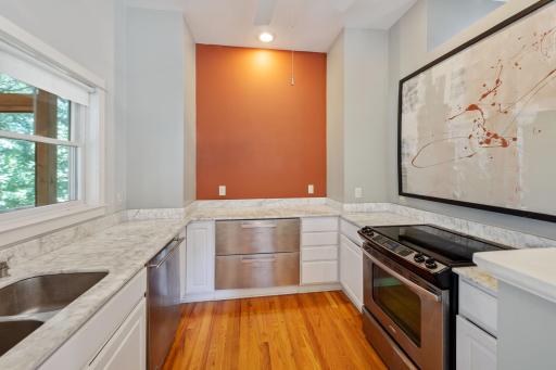 This modern kitchen features marble, stainless appliances and hardwood floors.
