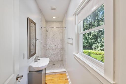 Main floor 3/4 bathroom features marble shower and hardwood floors.