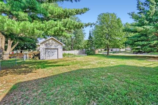 Ground-level view of huge fenced backyard with storage shed & garden space