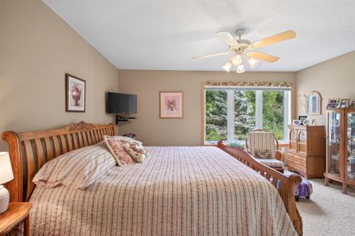 Spacious main floor primary bedroom complete with his/her closets and views of the wooded backyard.