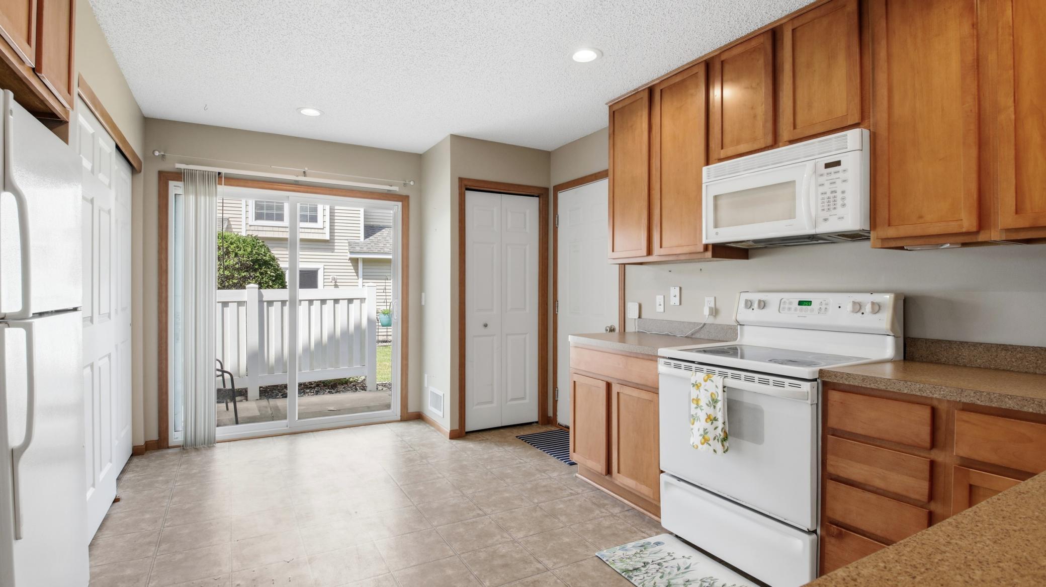 Spacious eat-in kitchen with ample cabinetry. Just outside is the patio. To the right is a handy closet and the garage entry.