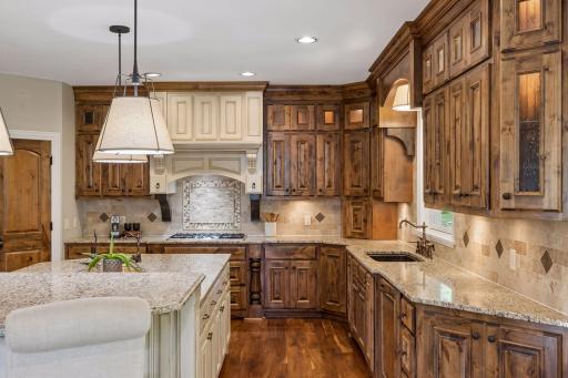 Other kitchen features include granite countertops, ceramic backsplash, a 5-burner gas cooktop with exhaust hood & a convenient appliance garage to tuck away your kitchen tools.