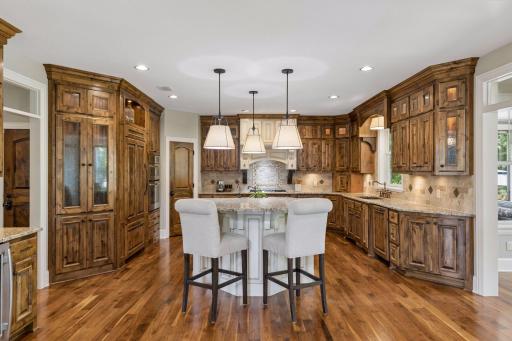 Kitchen features abundant knotty alder wood cabinets with pull-out drawers in the lower cabinets. The refrigerator and dishwasher use custom panel-ready designs to blend seamlessly with the cabinetry.