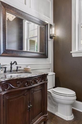 The main level includes a gorgeous half-bath with a custom furniture vanity, penny round tile floor and an ornate chandelier,