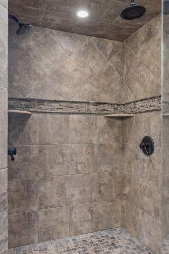 The spacious walk-in shower features ceramic tile, dual shower heads and a convenient built-in bench.