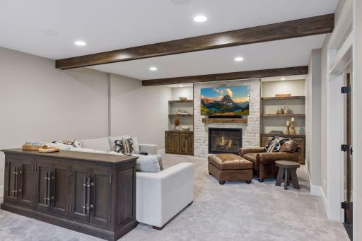 The cozy family room features built-in cabinets & shelves, a gas stone fireplace, recessed lights, beautiful wood beams and new carpet.