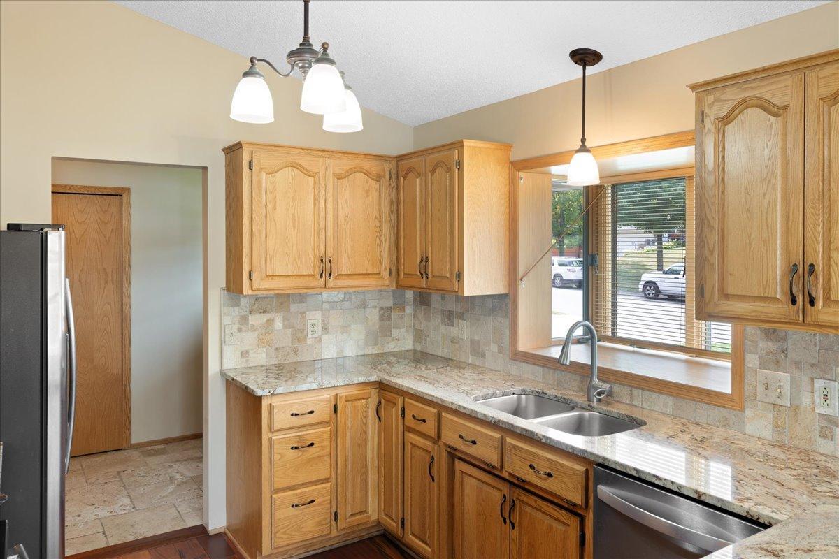 A Kitchen Designed for Everyday Living Granite counters, a tiled backsplash, stainless appliances, and a window above the sink create a warm, practical workspace.