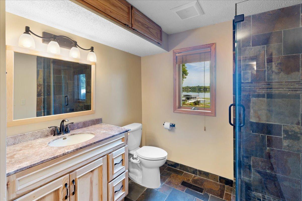 Start the Day Looking Toward the Water A spacious vanity, tiled shower, and lake-facing window create a bathroom that feels both comfortable and connected to its setting.