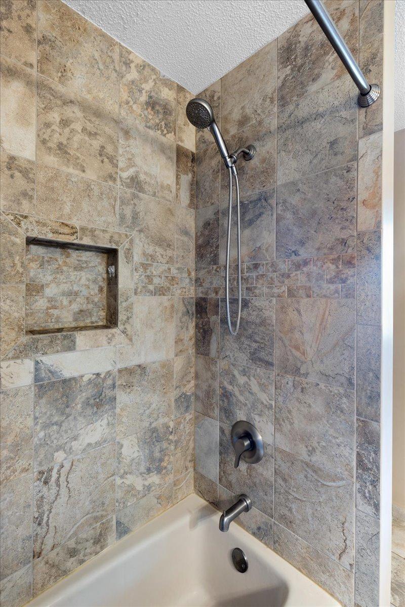 Thoughtful Finishes and an Unexpected View This updated bathroom pairs natural stone surfaces with a glass-enclosed shower and a window overlooking North Center Lake.