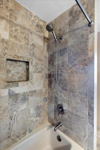 Thoughtful Finishes and an Unexpected View This updated bathroom pairs natural stone surfaces with a glass-enclosed shower and a window overlooking North Center Lake.