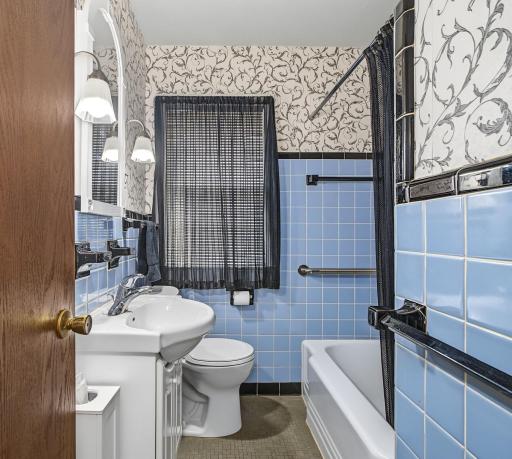 The sparkling full bathroom features a tiled floor and decorative wall tile to compliment.