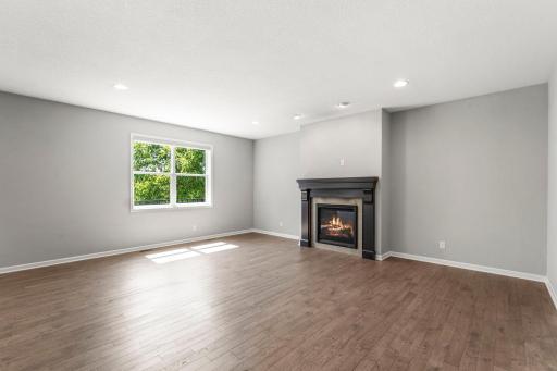 The living room is both comfortable and spacious, centered around a gas fireplace with tile surround and oversized windows that bring the outdoors in.