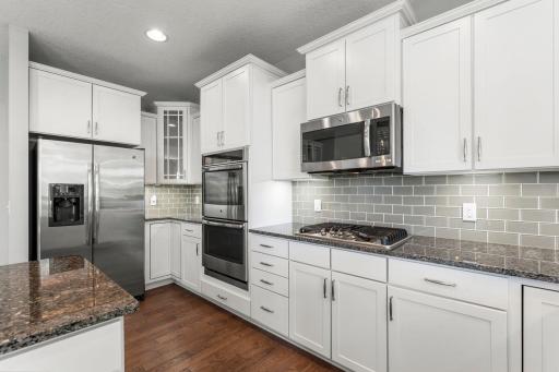 Tile backsplash, center island, plentiful cabinetry, wine storage, and a closet pantry.