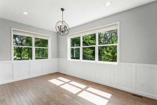 Just off the kitchen, the dining area is surrounded by windows and finished with detailed wainscoting and statement lighting.
