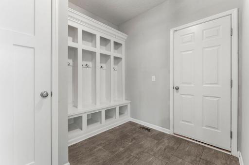 Everyday life is made easy with a designated mudroom featuring built-in bench seating, hooks, tile flooring, storage closet, and garage access.