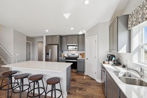 The heart of the home, the kitchen, has ample counter space with beautiful quartz counters, a center island with seating and storage, and a walk-in pantry! Photo of model, colors and options will vary.