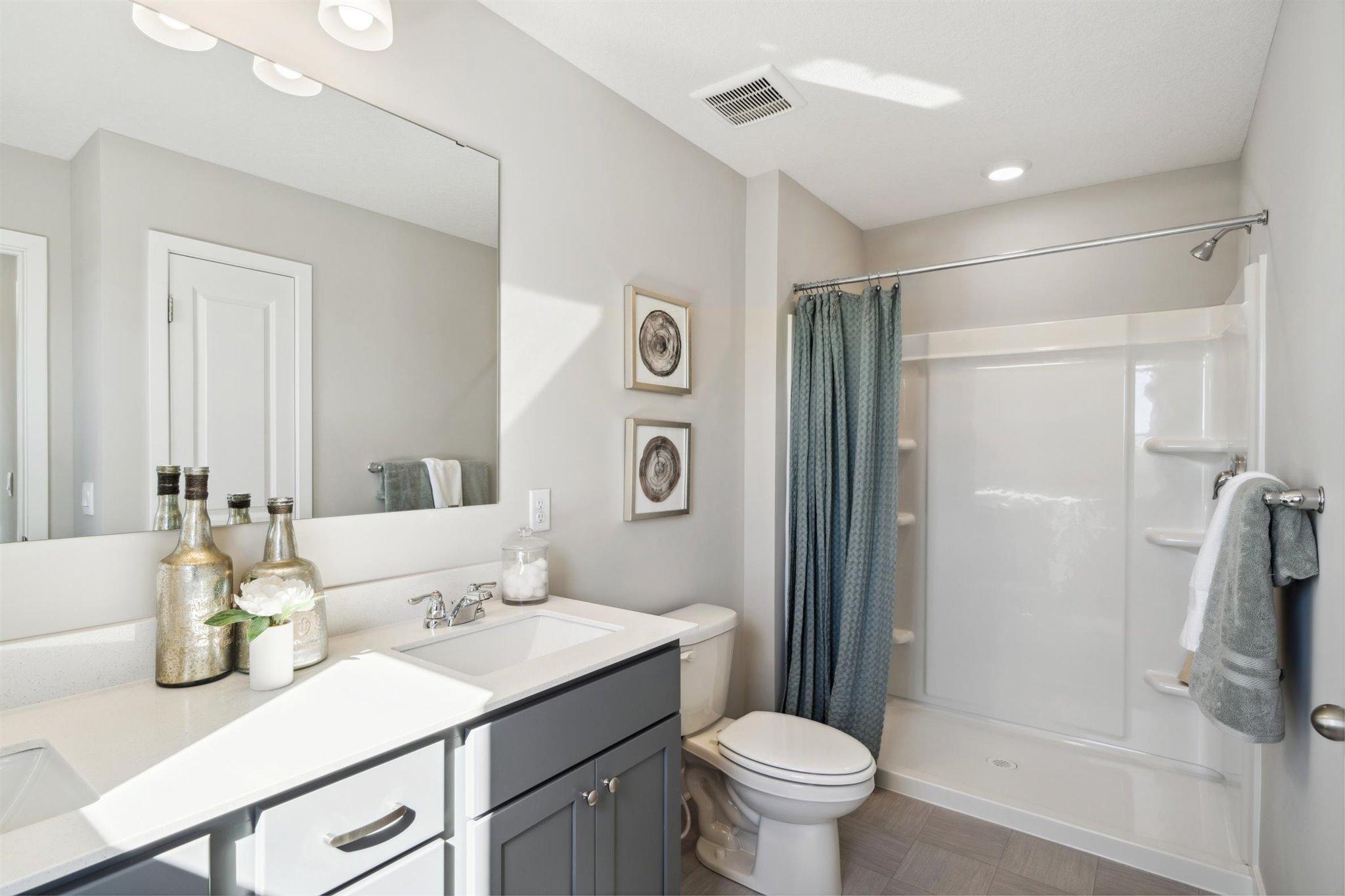 Dual vanity sinks, linen closets and window to allow natural light in primary bath. Photo of model, colors and options will vary.