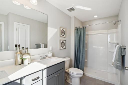 Dual vanity sinks, linen closets and window to allow natural light in primary bath. Photo of model, colors and options will vary.