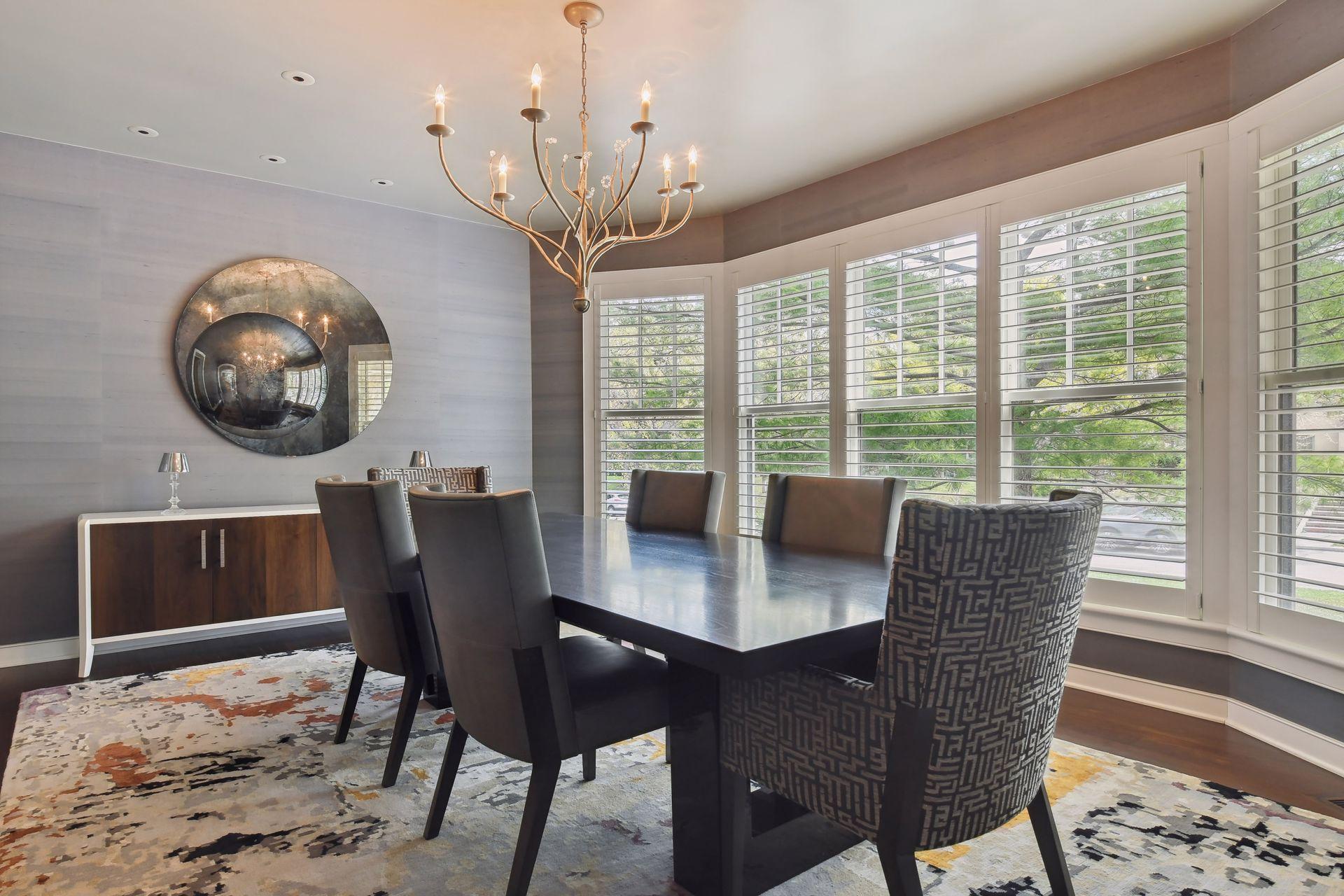 Subtle and refined wallpaper, plantation shutters, designer lighting and wood floors add interesting flair to the spacious formal dining room