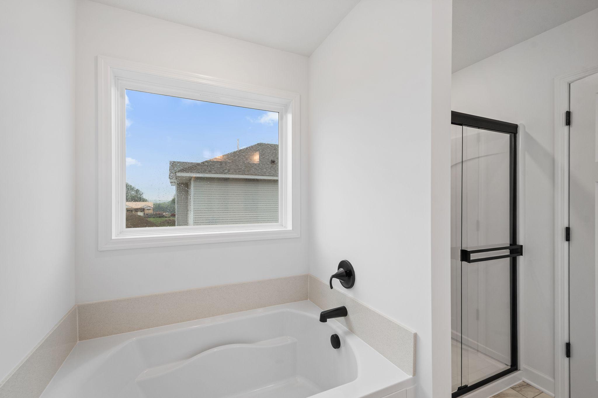 A glass-enclosed shower and separate soaking tub contribute to the bathroom’s spa-like atmosphere