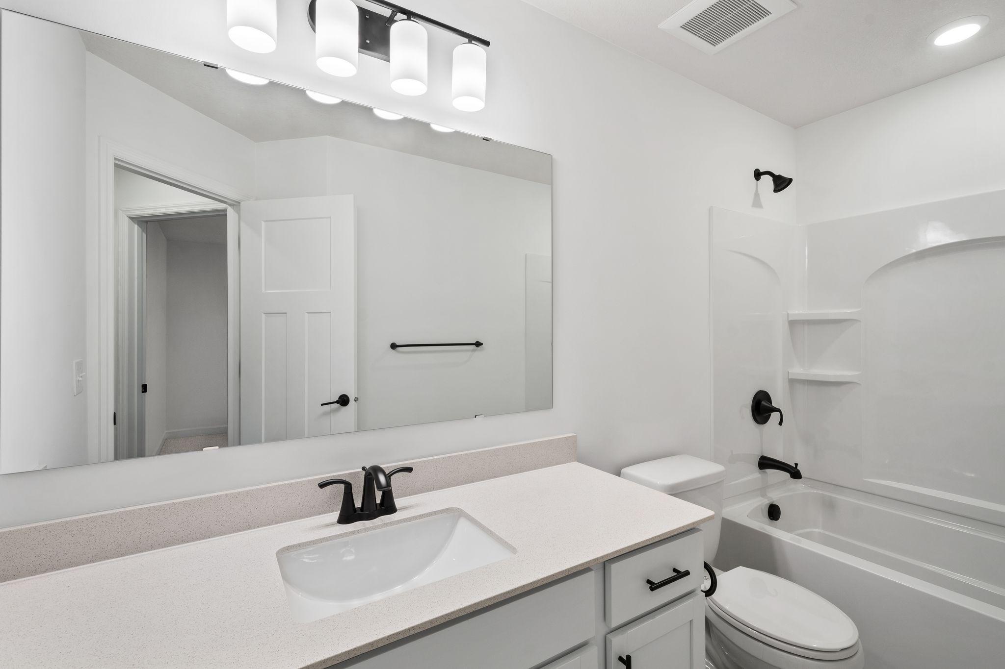 This full second-floor bathroom features a wide single vanity and shower-tub combination.