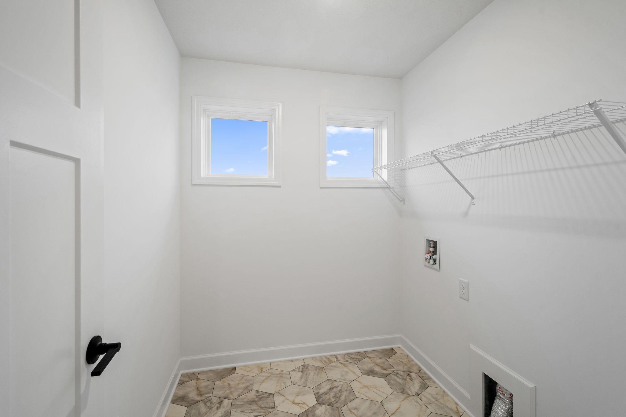 The laundry room features washer and dryer hook-ups and shelving for storage.