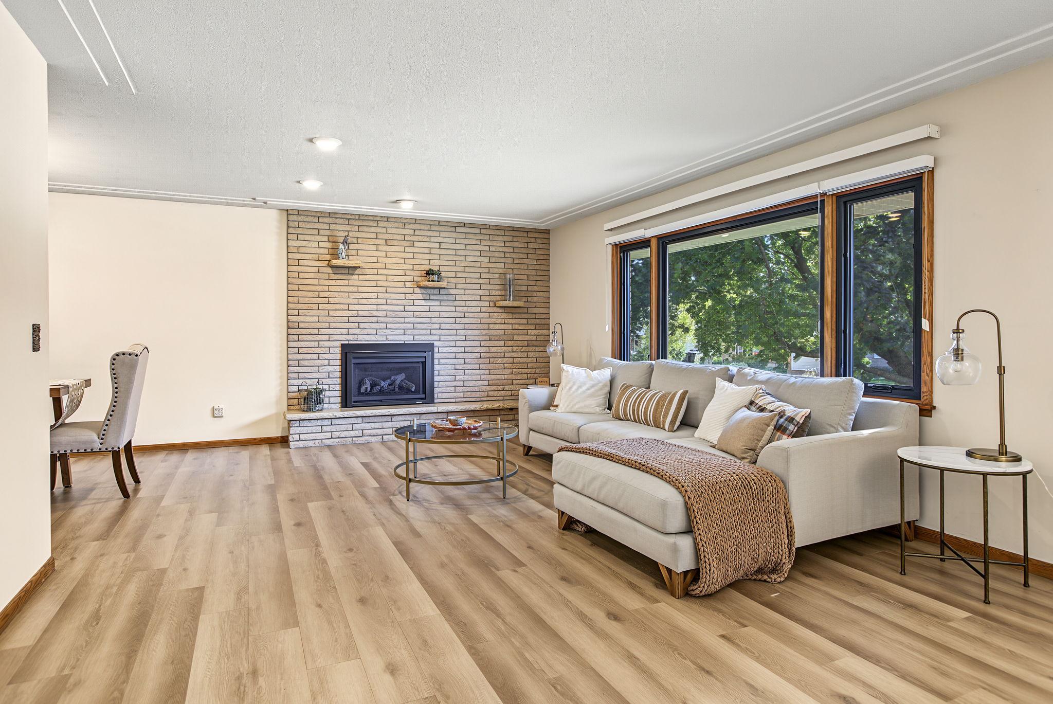 Enter into the bright open living room, featuring a gas fireplace surrounded by gorgeous midcentury brick.