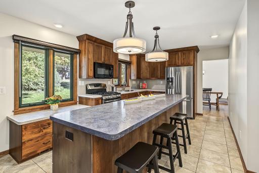 Kitchen features a large center island, stainless steel appliances, and windows overlooking the backyard.