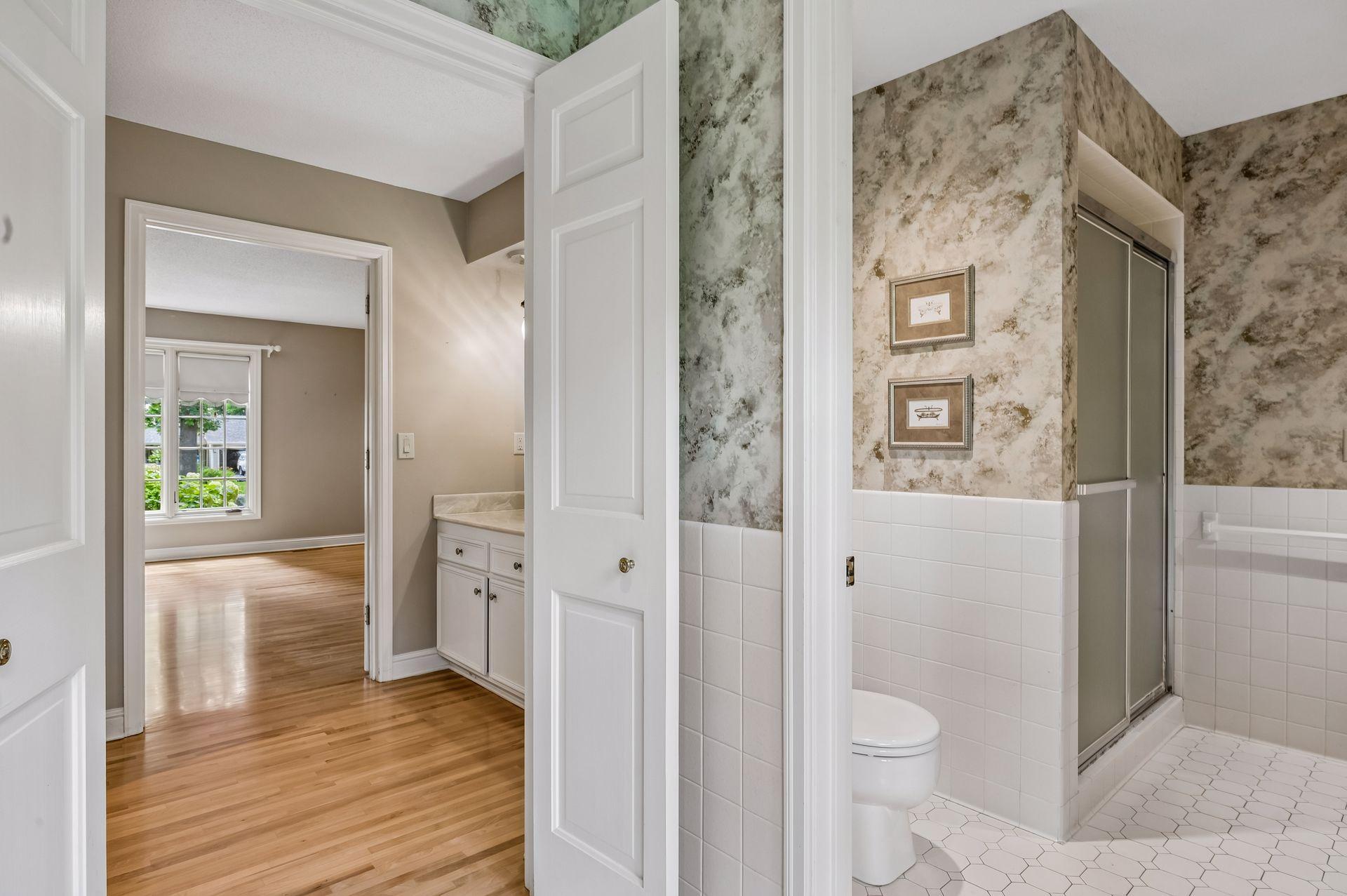 More double doors into primary bath tub/shower/stool/sink area
