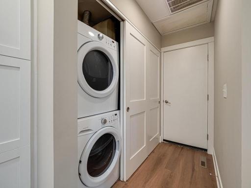 Convenient & Beautifully Finished Laundry: Full-size stacked washer and dryer are tucked neatly behind custom cabinetry, creating a clean, organized space