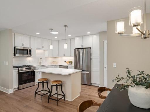 A stunning kitchen renovation featuring crisp new cabinetry, quartz countertops, custom tile backsplash, under-cabinet lighting, and premium GE appliances.