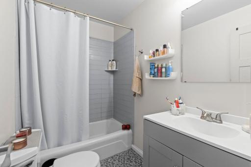 The full bathroom featuring a single vanity, tub and shower combination, and a nearby hallway linen closet for additional storage.