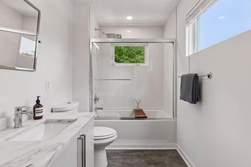 Second bath upstairs, also featuring white marble vanity top and large privacy windows.