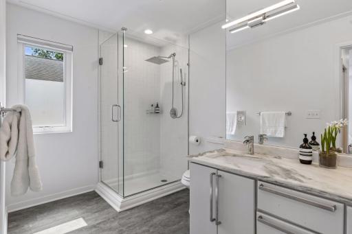 Primary suite bathroom, with white marble counter and step-in shower.
