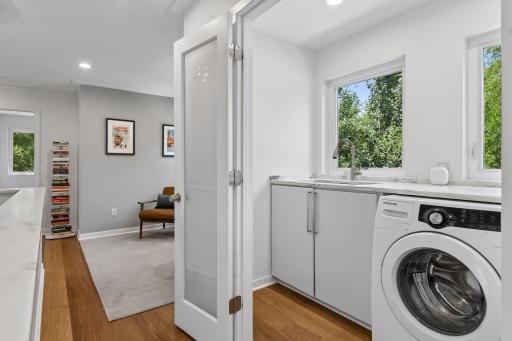 Upstairs laundry closet, also with white marble counters and frosted glass doors.